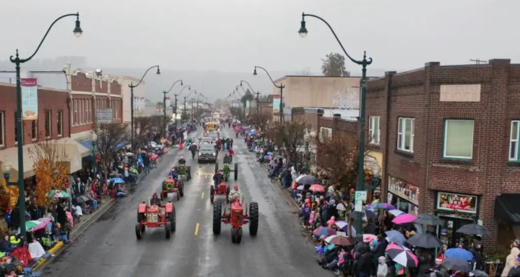 A tractor going down a street in a small-downtown-city